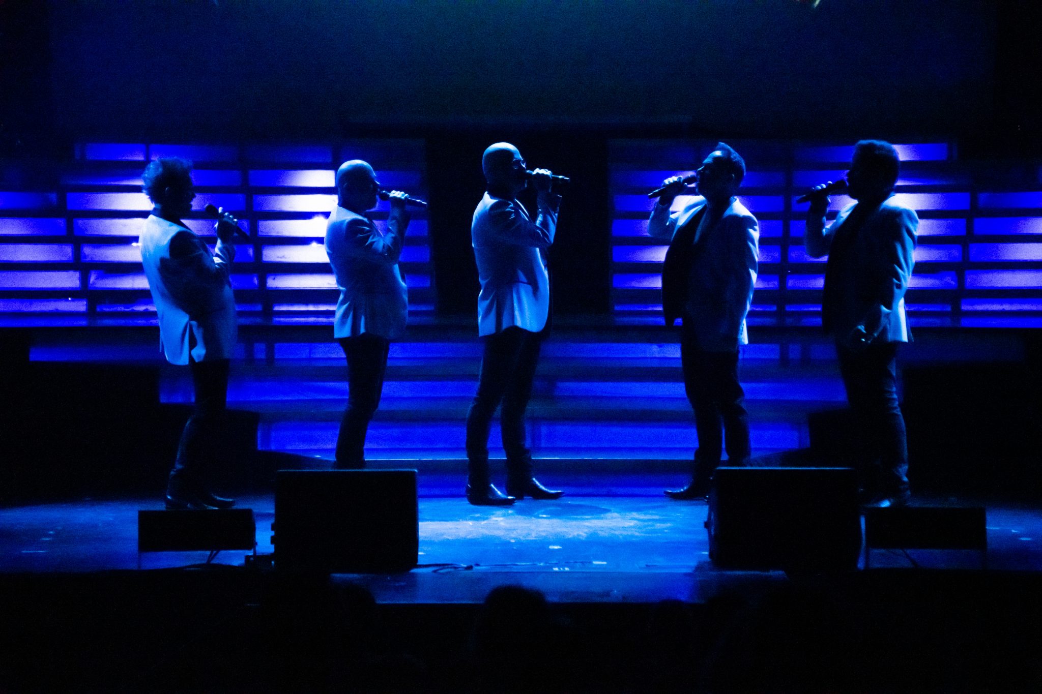 SIX performing bathed in blue stage lights